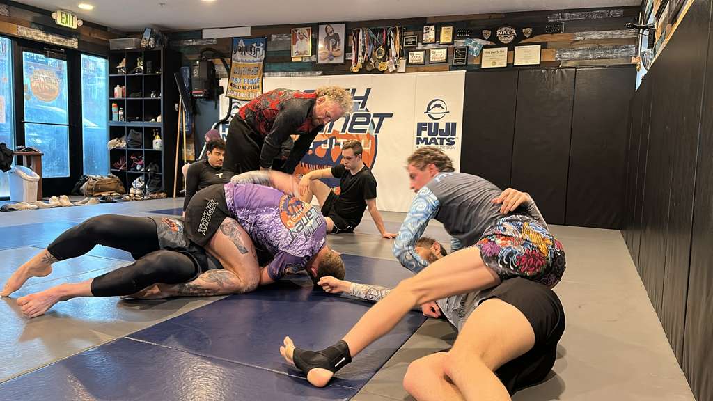 Adults training no-gi jiu-jitsu on the mats at 10th Planet Salt Lake City, with coach Dr. Amir Allam overseeing