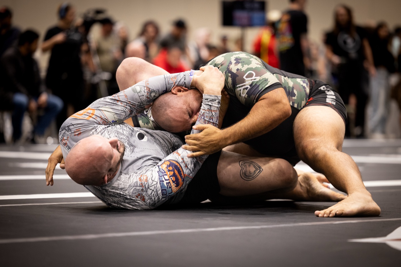 Two adults grappling no-gi at a jiu-jitsu competition