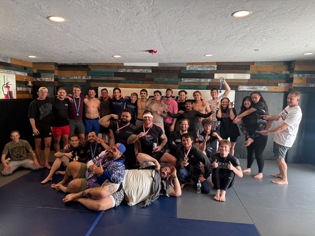 A big group at 10th Planet Salt Lake City posing with competition medals after a tournament