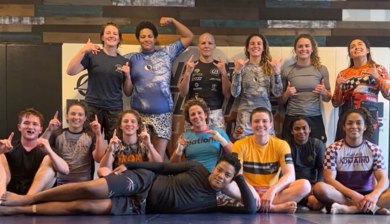 The women's class at 10th Planet Salt Lake City grouped together throwing shakas and finger guns after training